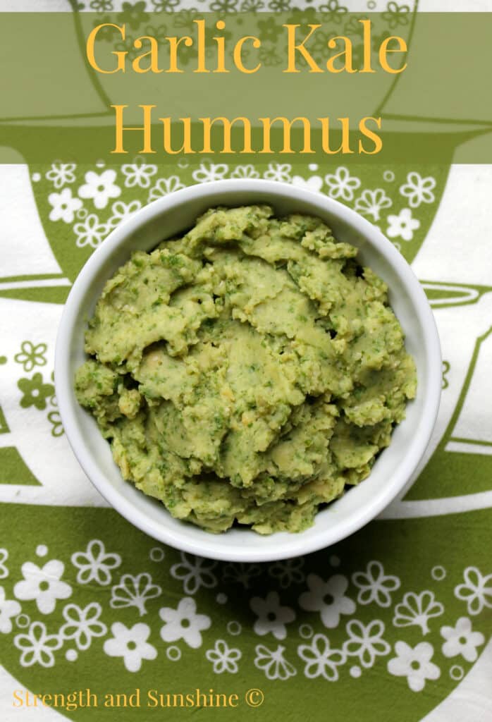 Green hummus in a white bowl on a green and white flowered napkin.