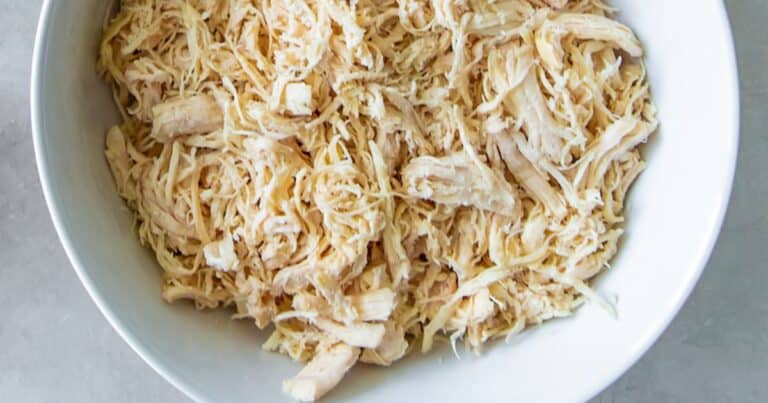 Low sodium instant pot frozen shredded chicken breast displayed in a white bowl on a white counter.