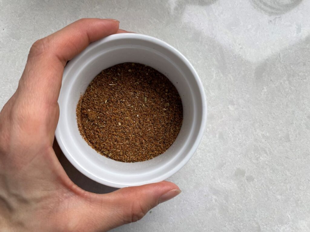 Finished mixed low sodium taco seasoning on a white countertop being held with a hand.