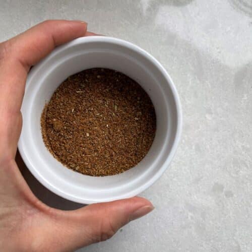 Finished mixed low sodium taco seasoning on a white countertop being held with a hand.