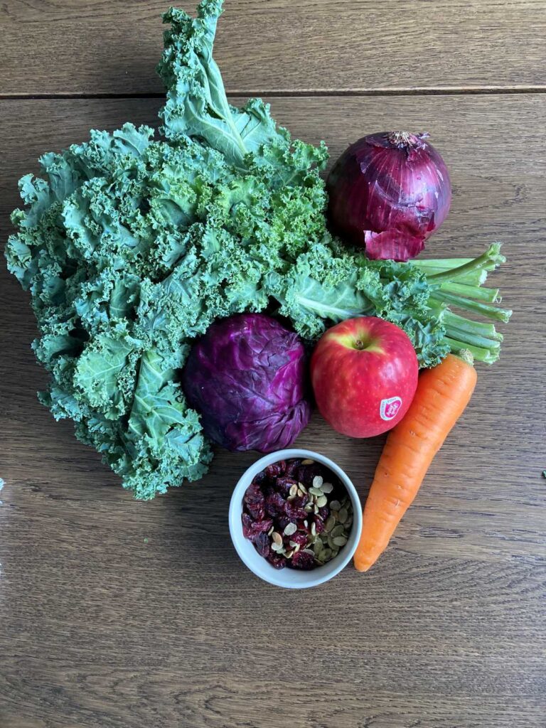 Ingredients in a kale slaw include kale, red onion, red cabbage, carrot, pumpkin seeds and cran-raisins.