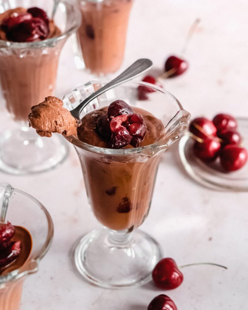 Heart healthy valentines day chocolate moose in a clear ice cream container topped with cherries.