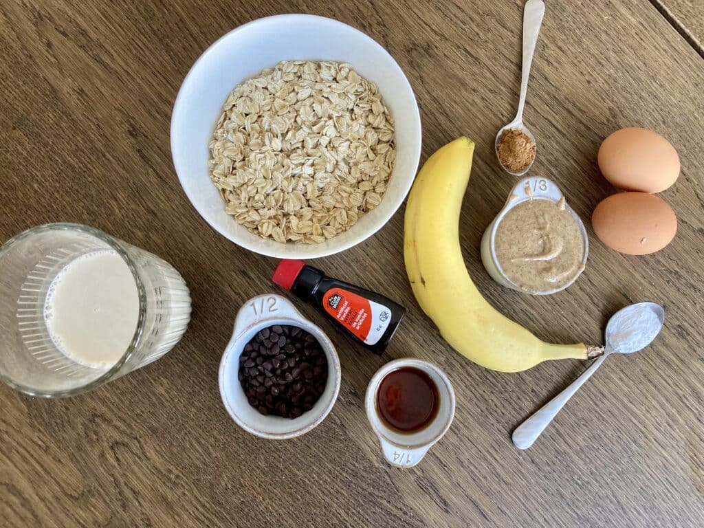 Ingredients in a cookie dough baked oats which includes milk, oats, banana, vanilla, eggs, peanut butter, cinnamon and chocolate chip.