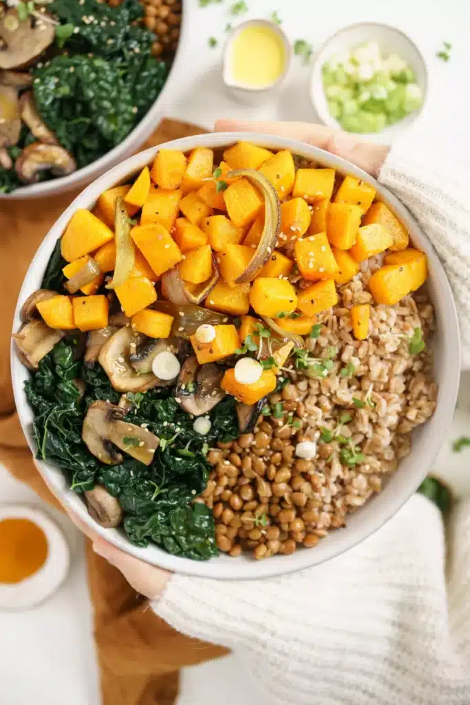 A low sodium lunch displayed in a white bowl filled with cubed butternut squash, cooked greens, lentils and brown rice. 