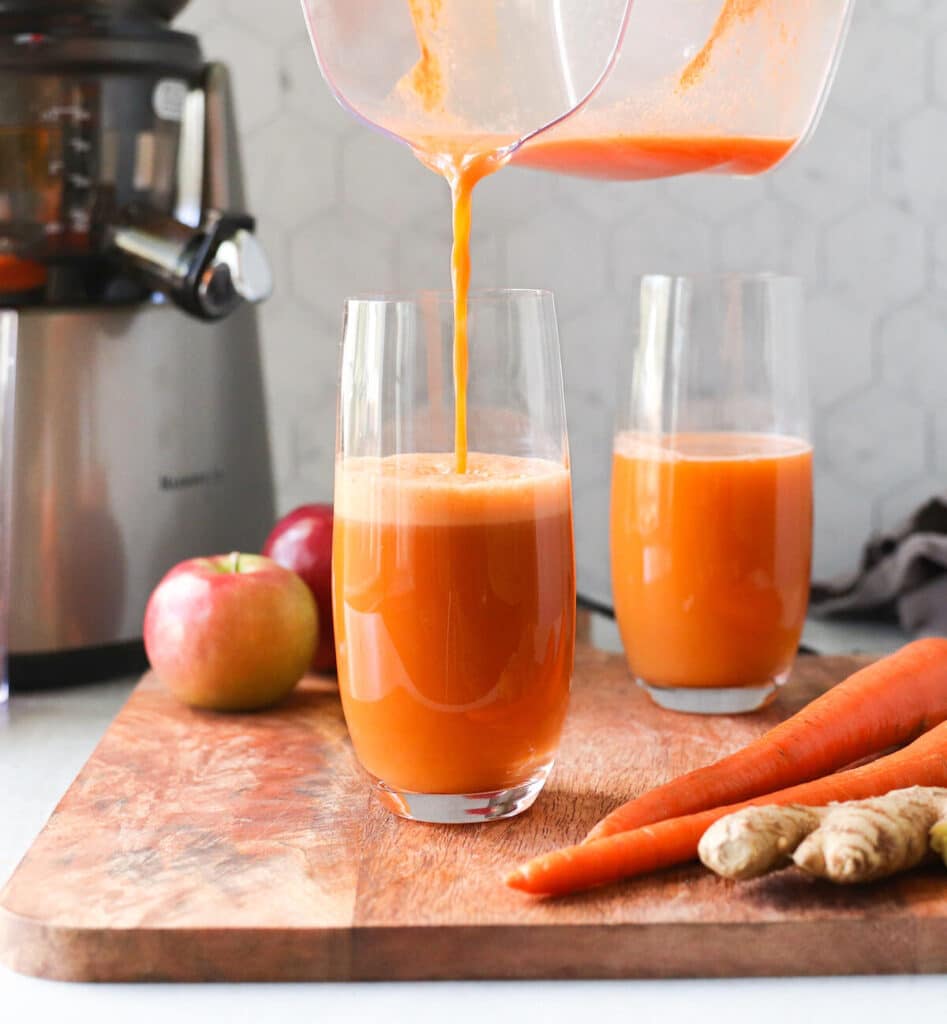 Orange juice to lower cholesterol presented in two tall clear glasses and one has a pitcher over it, actively being poured.