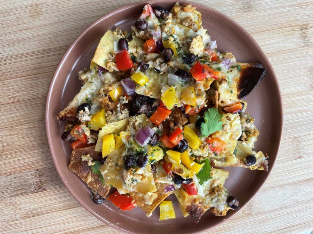 Cooked salmon nachos presented on a brown plate.