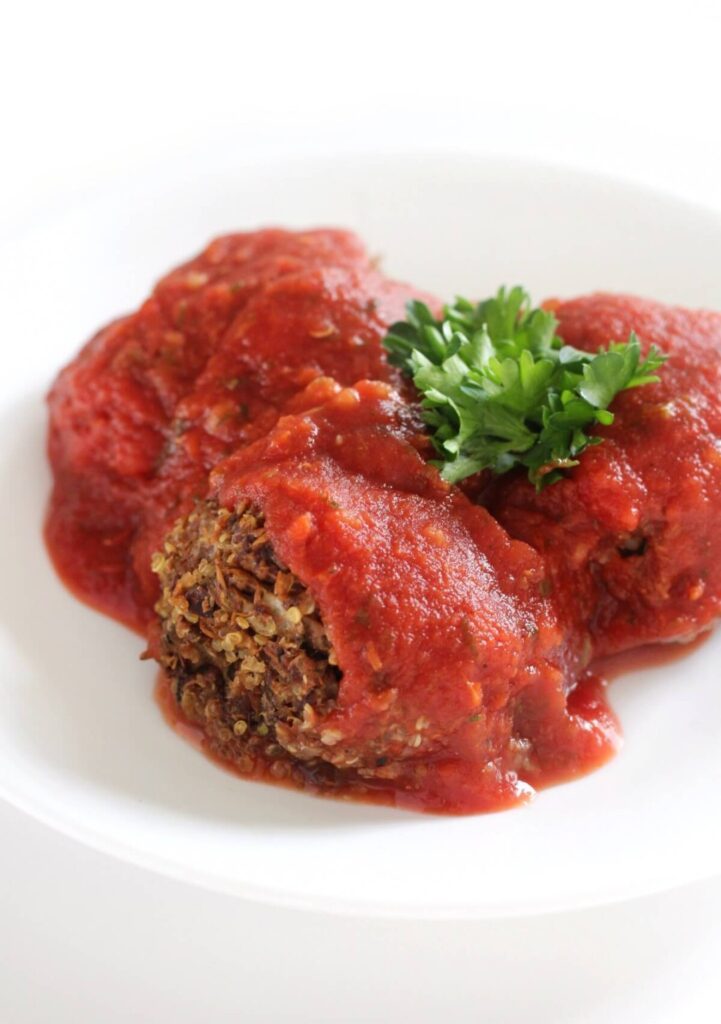 Three large meatballs covered in tomato sauce and topped with fresh herbs on white plate. Perfect for a low sodium dinner.