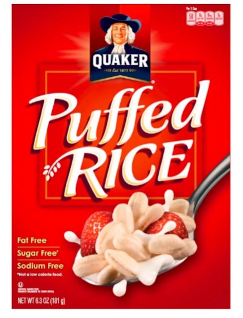 A red box of Quaker puffed rice. The box reads fat free, sugar free, and sodium free with an image of puffed rice and strawberries on a spoon.