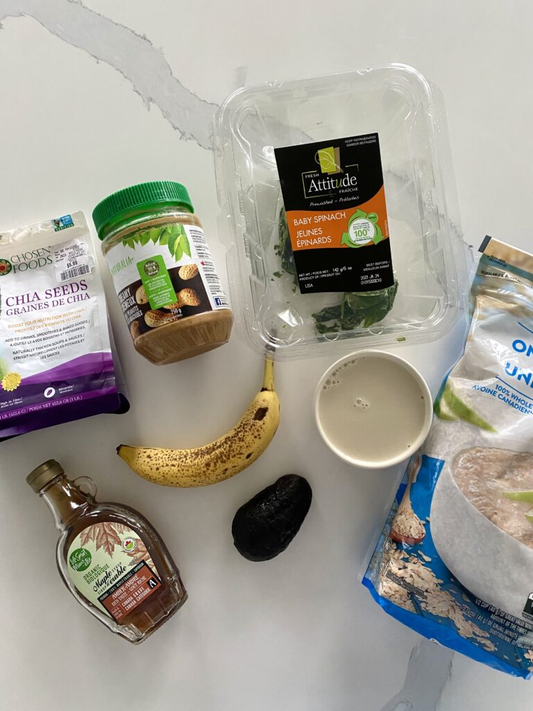Magnesium shake ingredients presented on marble counter in packages, including oats, peanut butter, spinach, banana, avocado, chia seeds and hemp seeds.