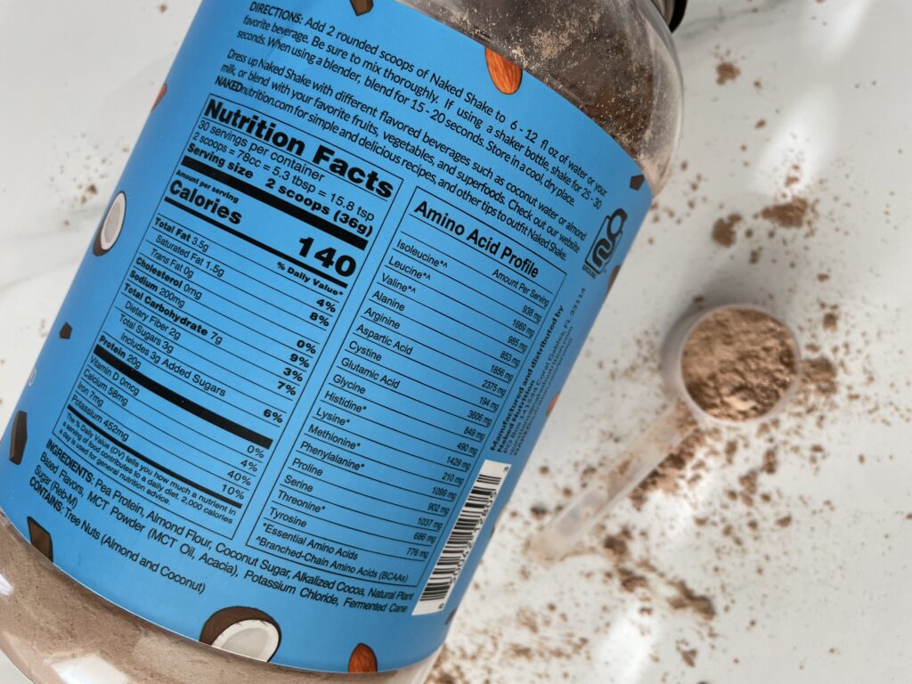 A blue container of a low sodium protein powder's container's food label on white marble with protein powder sprinkled around it.