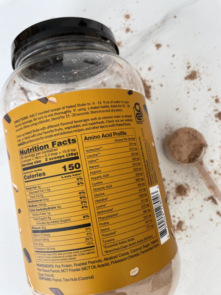 An orange container o a low sodium protein powder's container's food label on white marble with protein powder sprinkled around it.