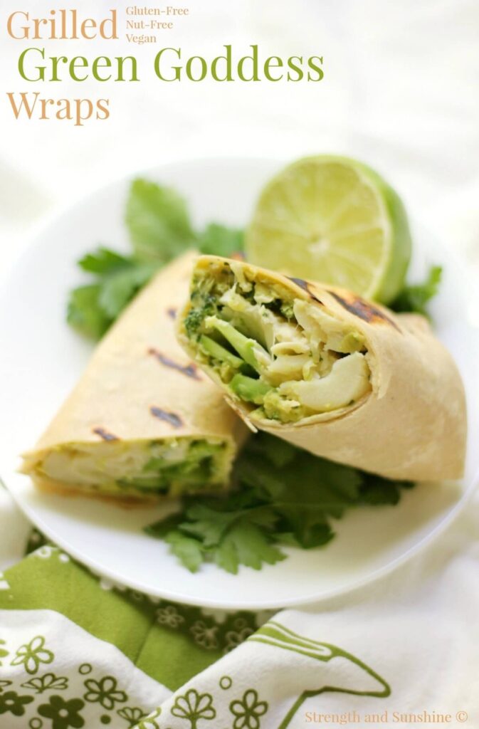 Grilled green goddess wrap pictured in a white dish atop herbs, with a lime next to the wrap.