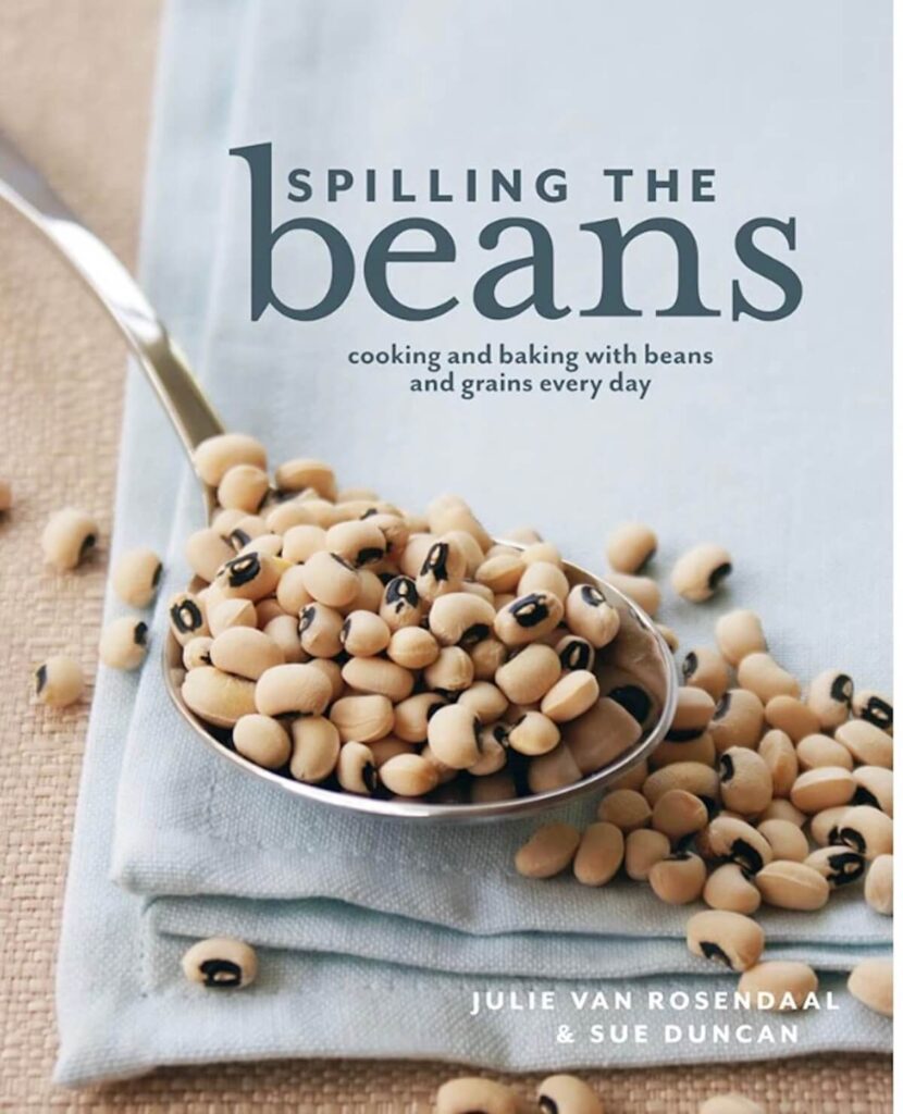 A cookbook with an image of beans in a spoon on the cover. The title reads "spilling the beans, cooking and baking with beans and grains everyday"