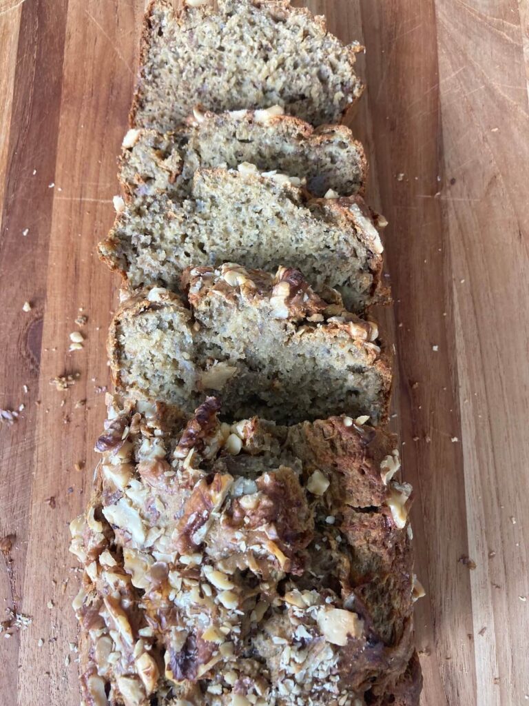 chia seed banana bread sliced on a wooden cutting board. 