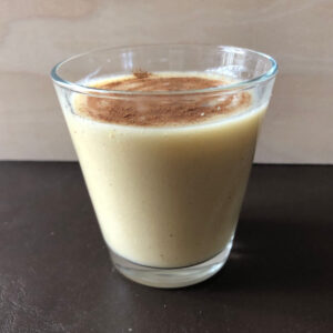 An image of chickpea milk in a glass, topped with cinnamon.