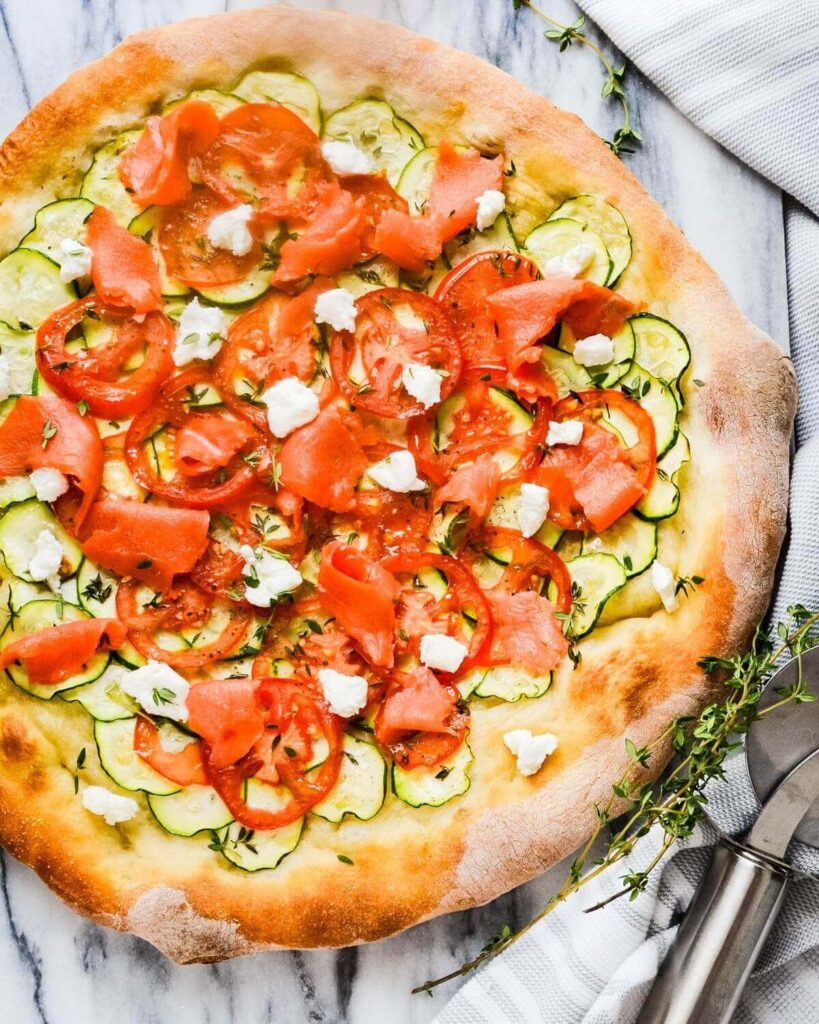 Smoked salmon pizza with goat cheese and zucchini slices.