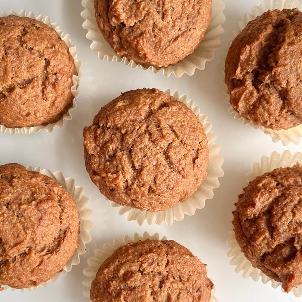 Date muffins pictured from above on a white countertop with muffin liners. 