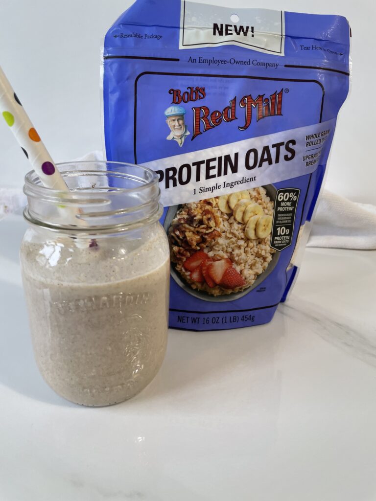 Oatmeal Cookie Smoothie on a white backdrop with Bob's Red Mill protein oats in the background.