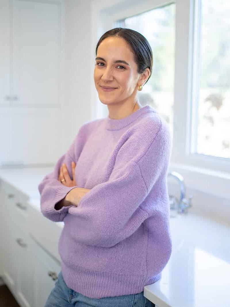 Veronica Rouse, The Heart Dietitian, leaning against a kitchen counter with arms crossed.