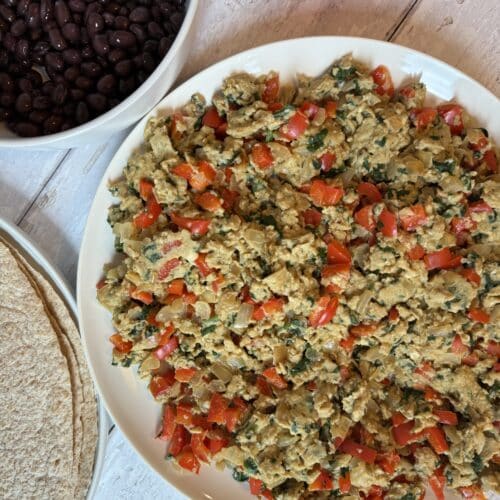 Black bean breakfast burrito made with scrambled eggs, mixed with veggies and whole wheat tortillas presented on a picnic table.
