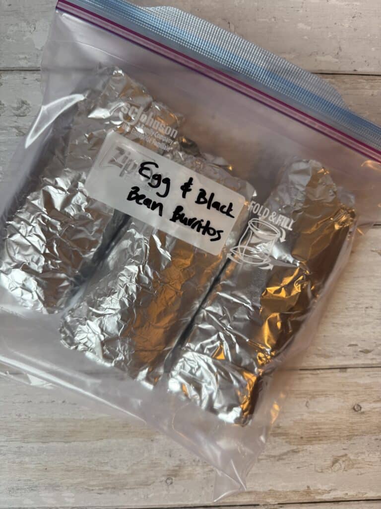 4 scrambled egg and black bean burritos wrapped in tin foil in a zip lock bag, ready for the freezer.