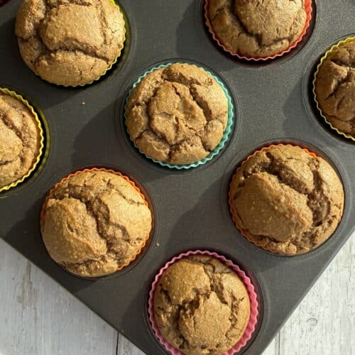 White bean muffins on a colourful muffin tin on a white picnic table.