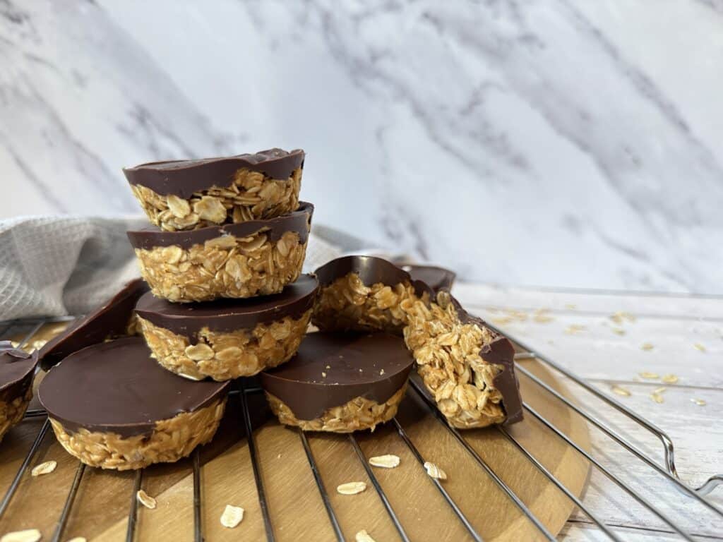 4 Ingredient peanut butter oat cup low cholesterol dessert pictured on wood cutting board with grey towel in background.