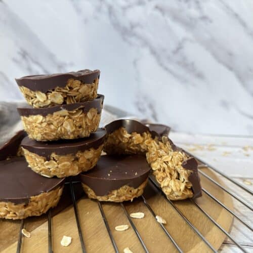 4 Ingredient peanut butter oat cup low cholesterol dessert pictured on wood cutting board with grey towel in background.