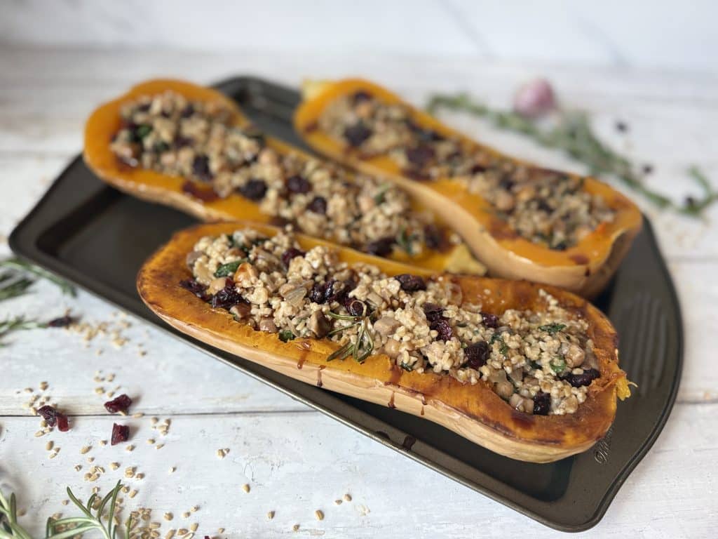 OT stuffed squash presented on a baking dish beside rosemary and garlic cloves.